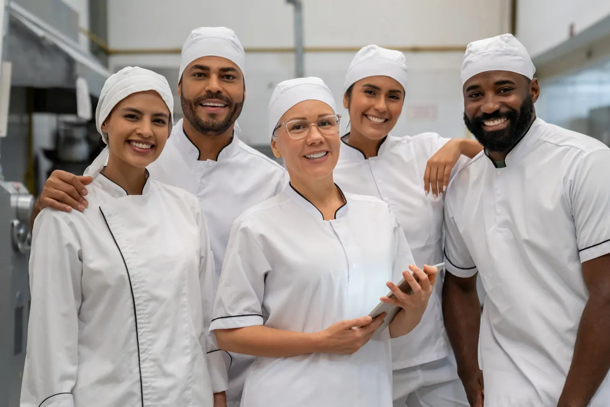 Team medewerkers in witte bedrijfskleding in een productie- of foodomgeving.