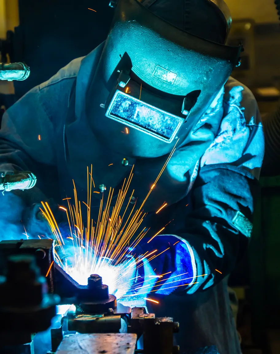 Lasser aan het werk met metaal en vonken in een werkplaats.