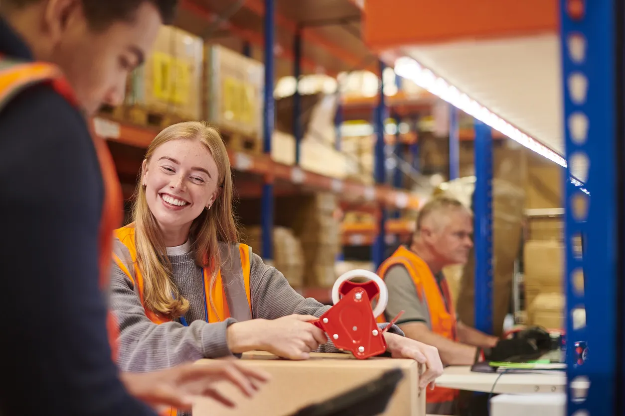 Medewerkers in een magazijnomgeving die pakketten verpakken en voorbereiden voor verzending.