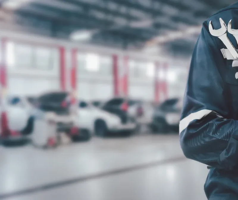 Monteur in werkplaats met gereedschap tijdens auto-onderhoud.