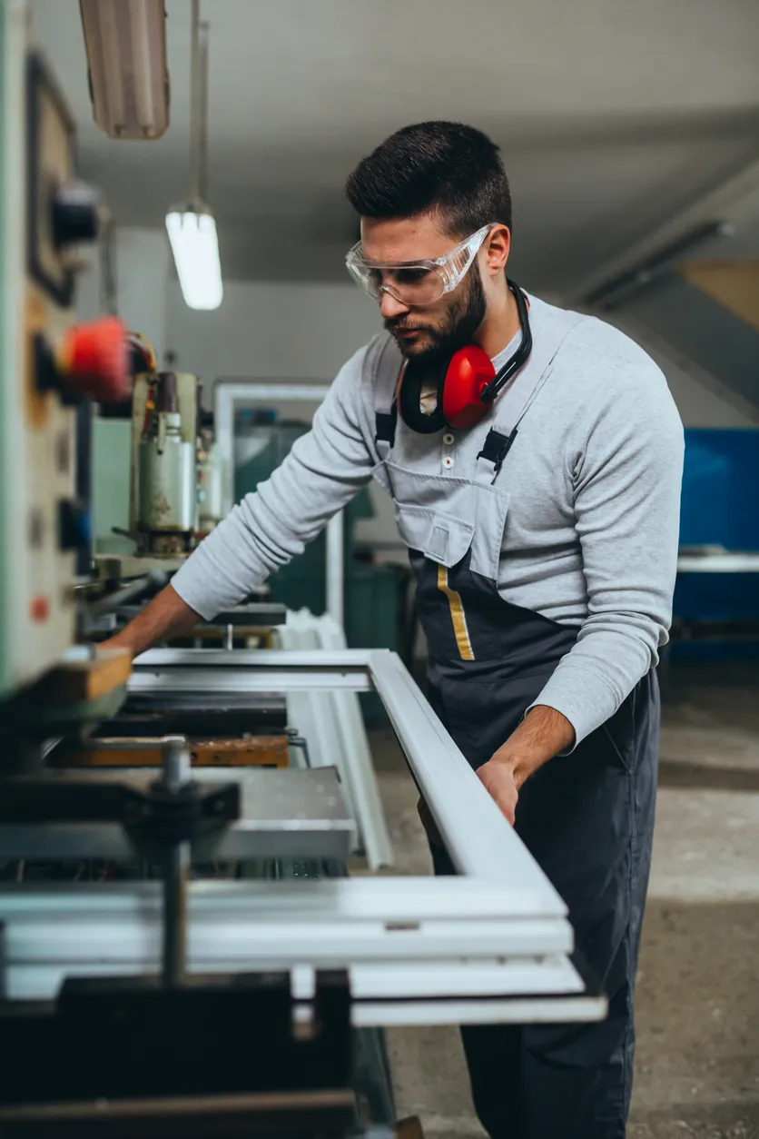 Medewerker in de productie die werkt aan een machine in een fabriek.