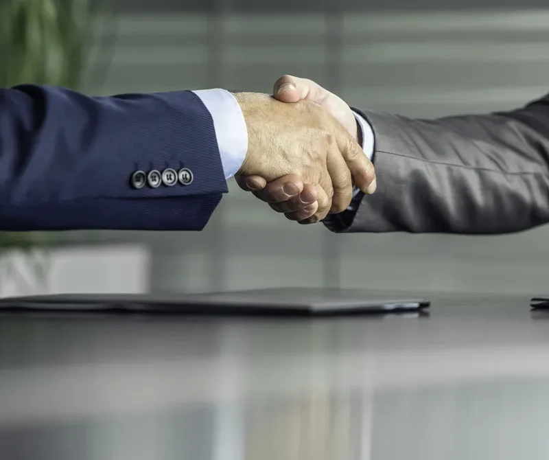 Twee personen in zakelijke kleding die elkaar een hand geven bij het maken van een afspraak.